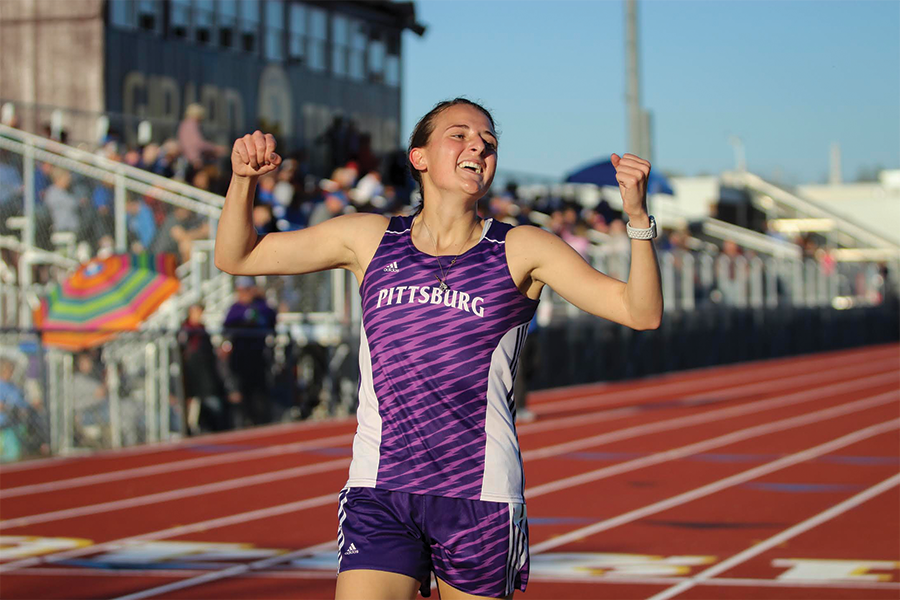 Senior McKenzie Wilks throws her hands in the air with joy after she crosses the finish line at the Girard Relays. 
