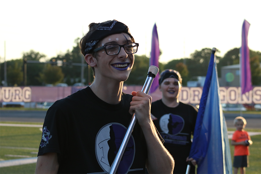 ABOVE: Junior Dominic Hyatt (front) and sophomore Lane Phifer (back) smile in front of the crowd before their halftime show at the Dragons football game last week against Blue Valley North. Hyatt and Phifer are the first males to join color guard since it was reintroduced in 2014. 