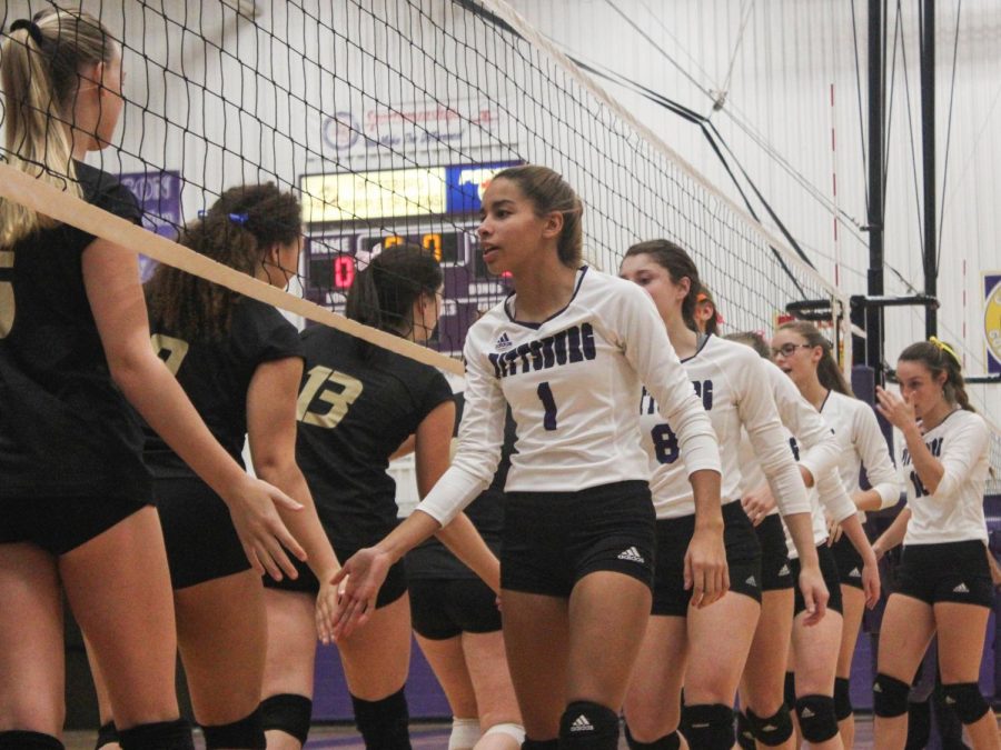 Preparing to start the game against Paola, junior Faith Turner and members of the varsity team slap hands before the first match, Phs defeated Paola in three matches, 25-11, 25-22,25-20. 