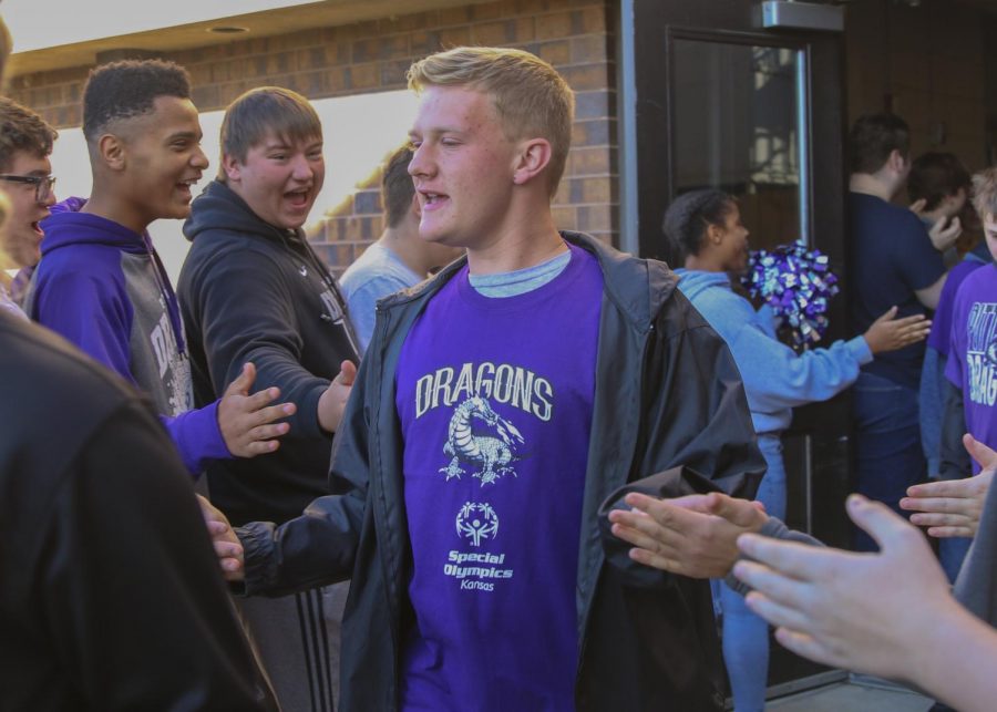 Kids competing in the special olympics walk their way out as other students cheer them on.