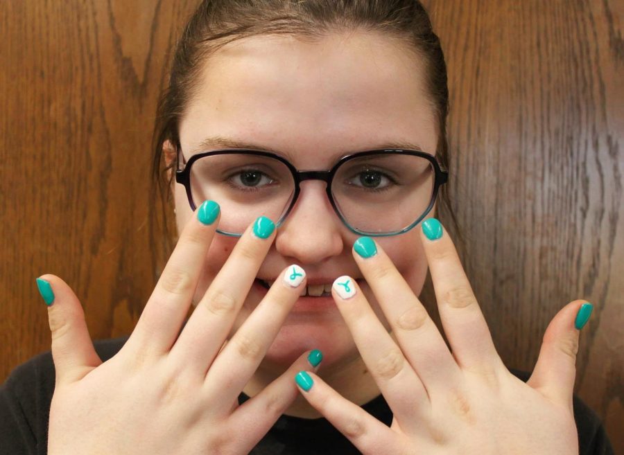 Junior Emily Wachter poses with her nails which are decorated with Tourette's awareness colors and art.