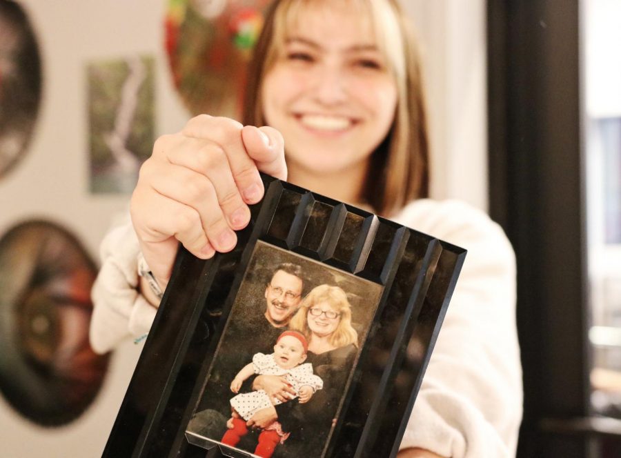 Senior Franchesca Brownhanney poses with a family photo from when she was first adopted. 