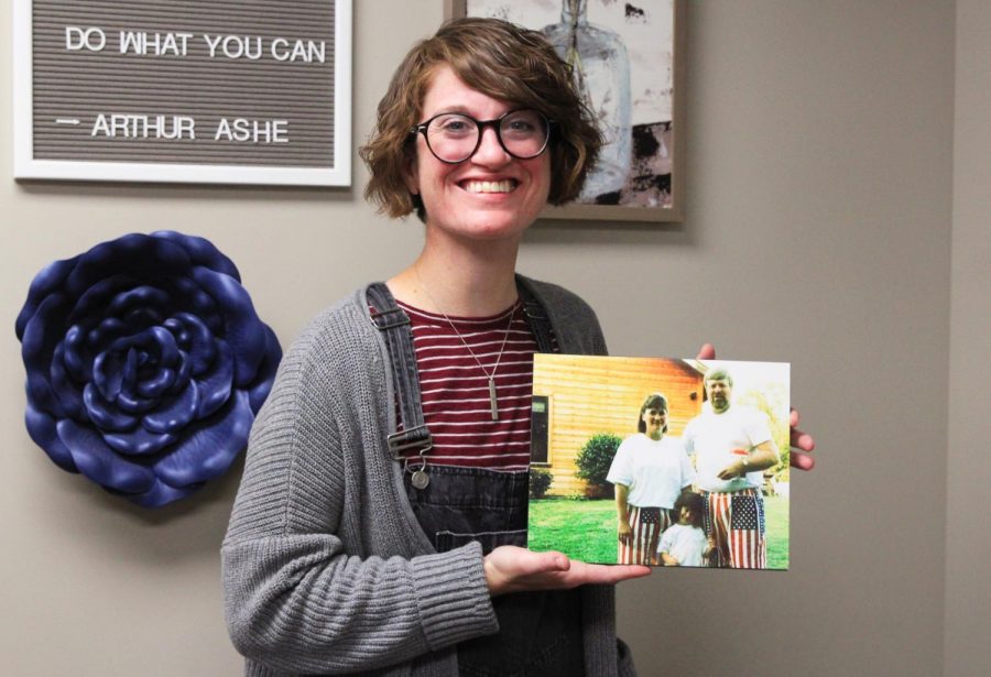 School counselor Stef Loveland poses along side a photo of her and her adoptive parents. 