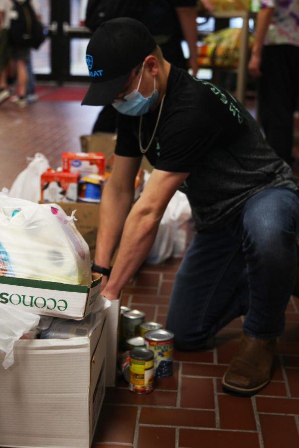 Freshmen Cooper Parker helps stack food and hygiene products that were donated to the food drive hosted by the Culinary Dragons and Student Council.