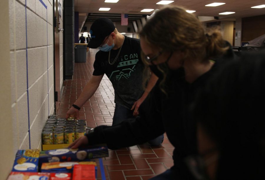 Senior Maddie Ellis (front) and freshmen Katie Davis (middle) and Cooper Parker (back) help stack food and hygiene products that were donated to a food drive hosted by the Culinary Dragons and Student Council.