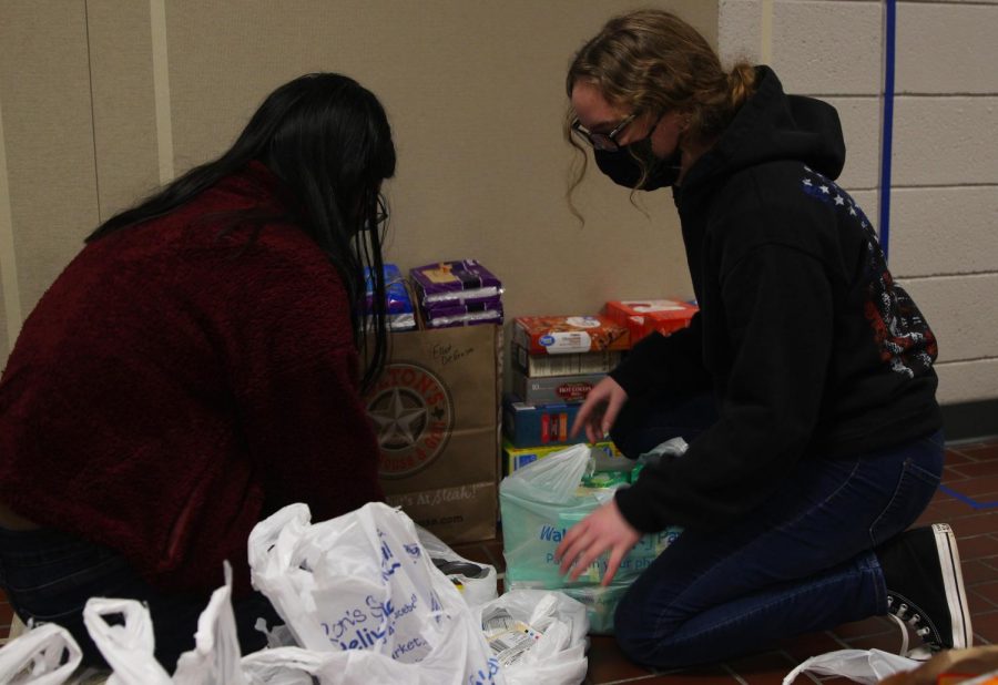 Senior Maddie Ellis (left) and freshmen Katie Davis (right) help stack food and hygiene products that were donated to a food drive hosted by the Culinary Dragons and Student Council.