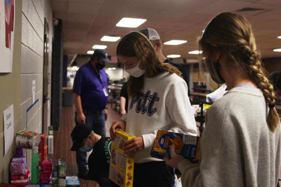 Junior Abby Painter stacks food that was donated to a food drive hosted by the Culinary Dragons and Student Council.