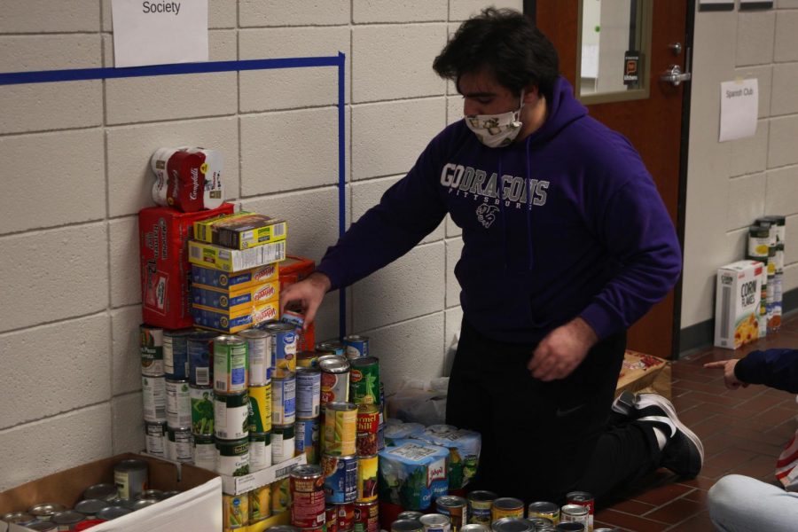 Senior Christopher Saman stacks food that was donated to a food drive put together by the Culinary Dragons and Student Council.