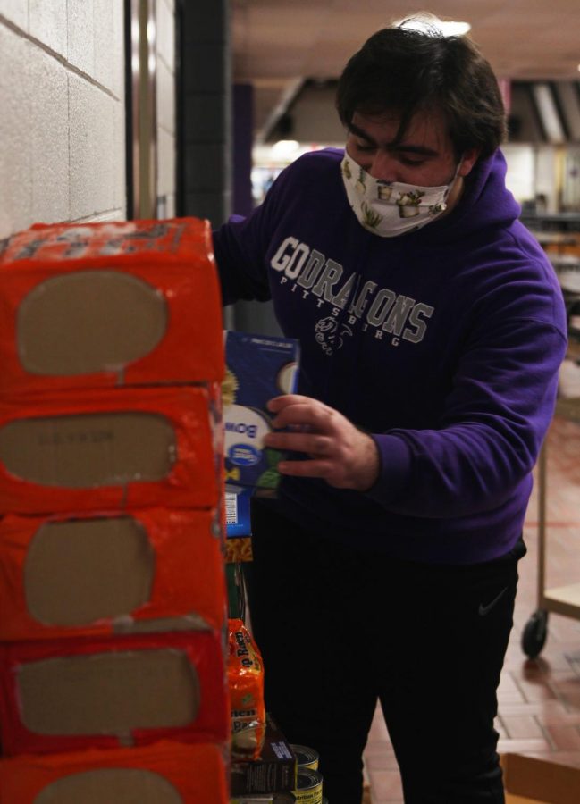 Senior Christopher Saman stacks food that was donated to a food drive put together by the Culinary Dragons and Student Council.