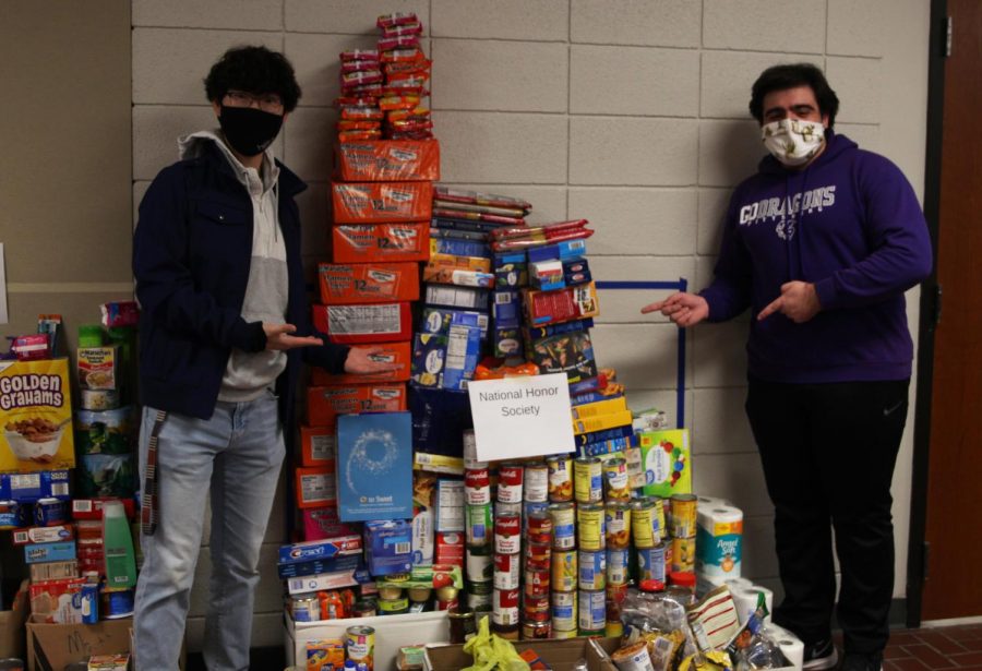 Seniors Jospeh Lee (left) and Christopher Saman (right) pose next to the donations National Honors Society made to a food drive the Culinary Dragons and Student Council put together.