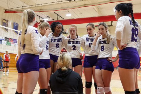 Varsity volleyball team huddles together during a game.
