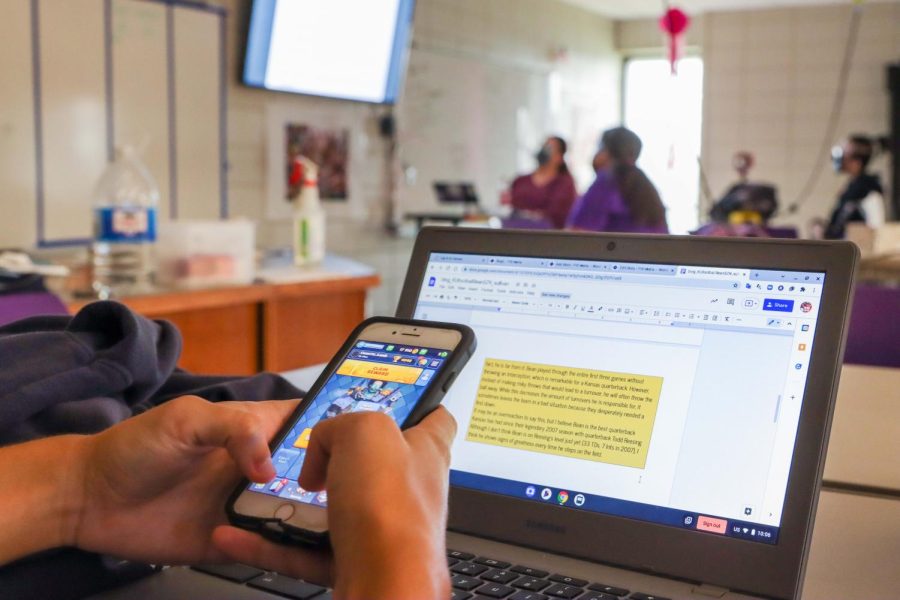 A student in class is playing Clash Royale rather than paying attention to the class lecture.