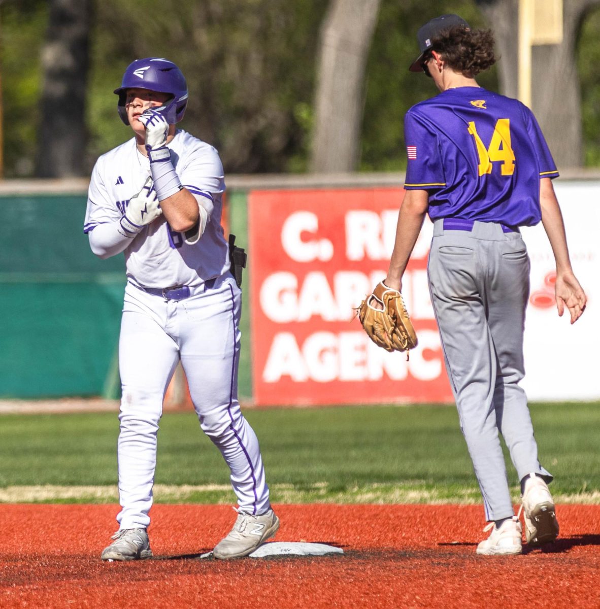 After successfully sliding into second base and beating the throw from the outfield, senior Tucker Akins calls time to give Coach Dwayne Vaughn his batting gloves. 